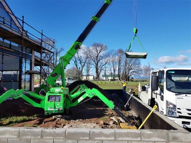a green mini crane for rent to work on carrying and lifting loads in the United States